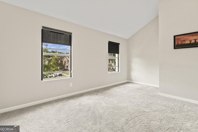 spare room featuring carpet flooring and vaulted ceiling