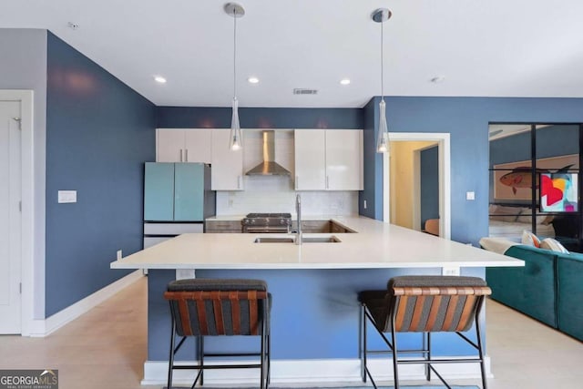 kitchen with wall chimney range hood, white cabinets, a kitchen bar, light hardwood / wood-style floors, and backsplash