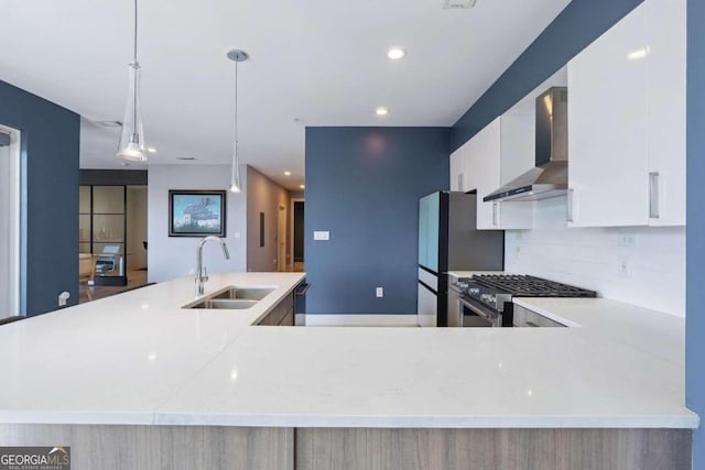 kitchen featuring white cabinets, stainless steel stove, wall chimney range hood, sink, and backsplash