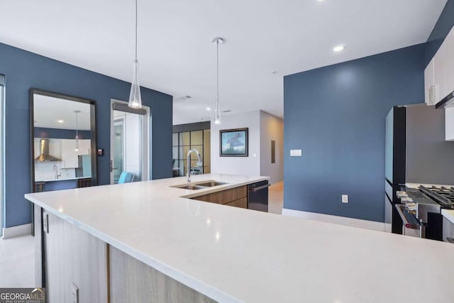 kitchen featuring pendant lighting, wall chimney exhaust hood, sink, black dishwasher, and high end stainless steel range