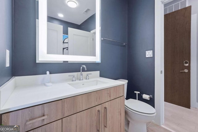 bathroom featuring hardwood / wood-style flooring, toilet, and vanity