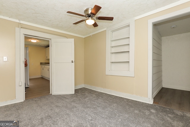 empty room featuring built in shelves, a textured ceiling, hardwood / wood-style flooring, and ceiling fan