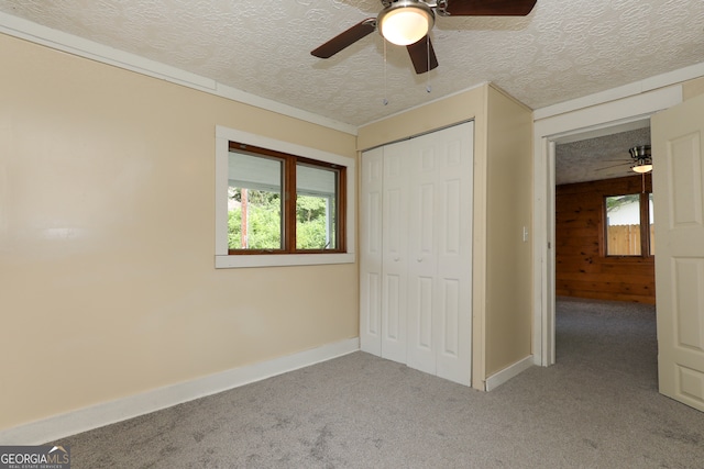 unfurnished bedroom featuring a textured ceiling, a closet, carpet floors, and ceiling fan