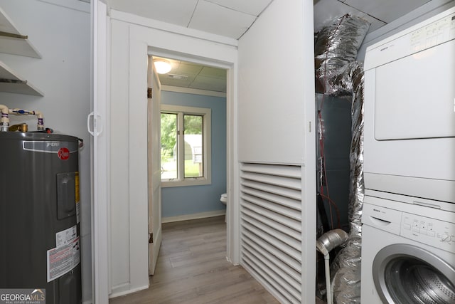 clothes washing area featuring water heater, stacked washing maching and dryer, and light hardwood / wood-style floors