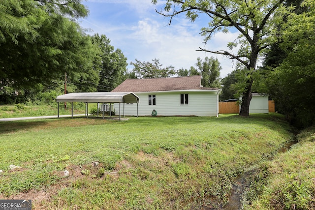 view of front of property featuring a carport, an outbuilding, and a front lawn