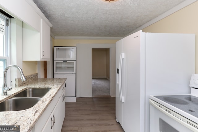 kitchen with white stove, hardwood / wood-style floors, sink, light stone counters, and white cabinetry