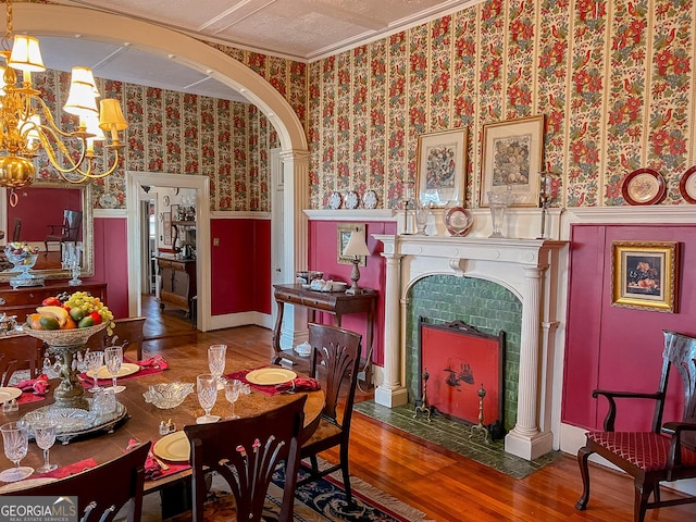 dining area featuring a tiled fireplace, wood-type flooring, and a chandelier