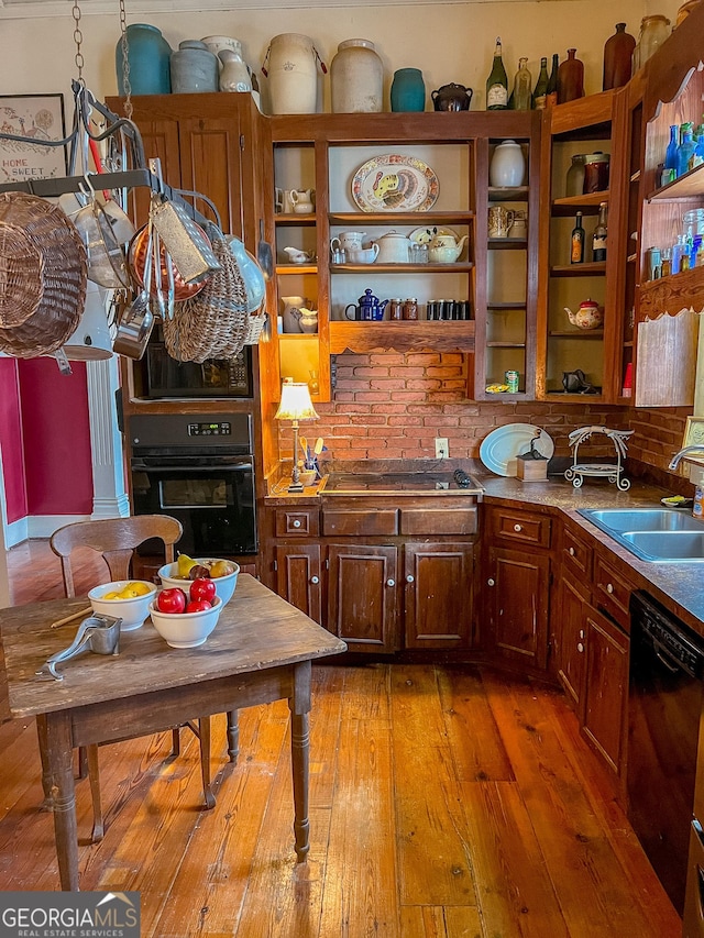 kitchen with sink, black appliances, and light hardwood / wood-style floors