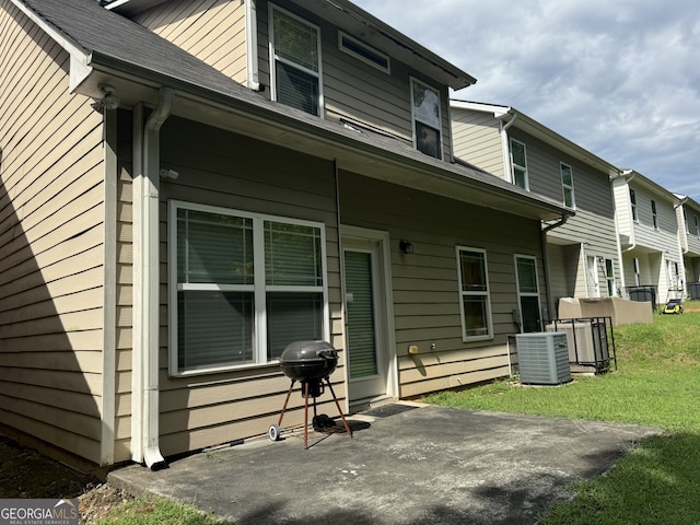 back of property with a yard, central AC, and a patio area