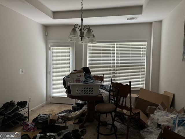 dining space with a chandelier, a raised ceiling, and carpet