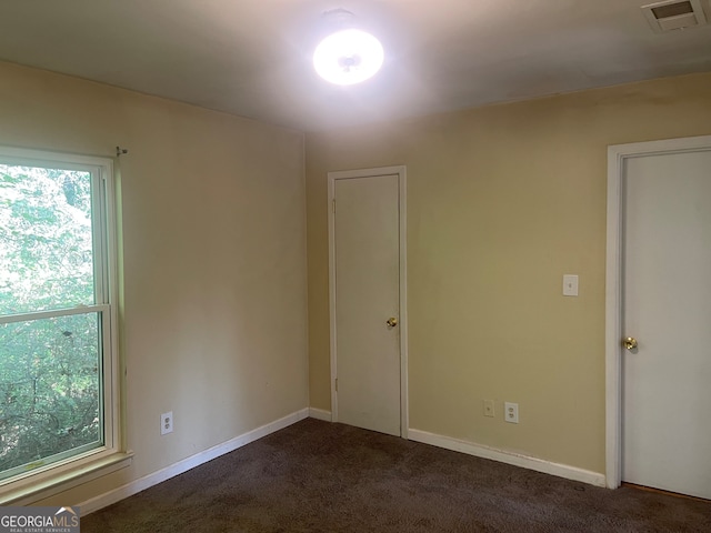 spare room featuring dark colored carpet