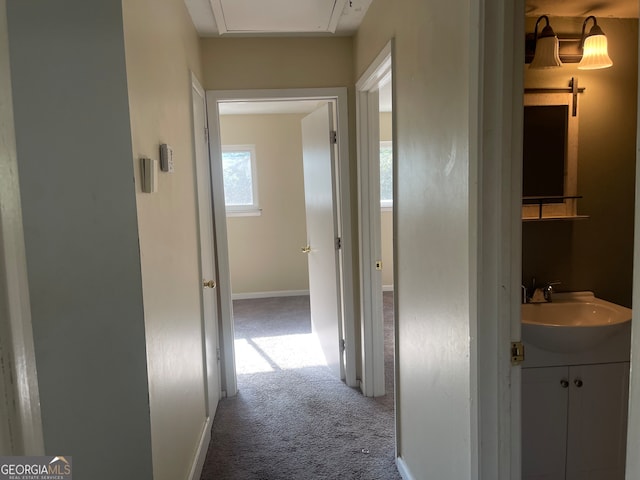 corridor featuring sink and light colored carpet