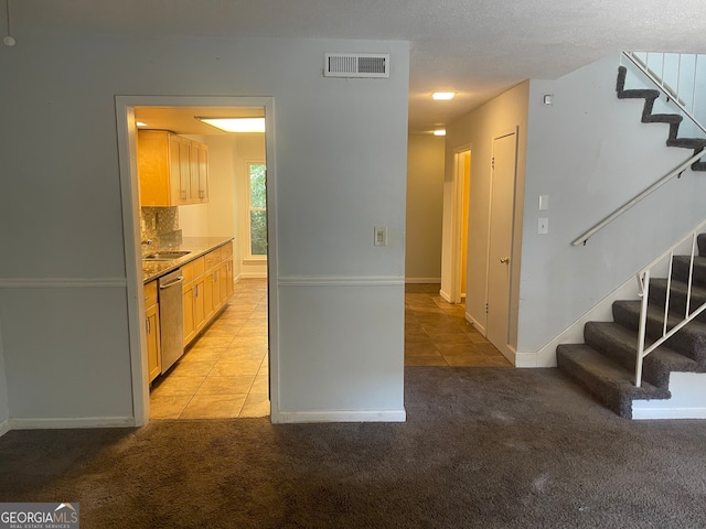 kitchen featuring a textured ceiling, light carpet, and dishwasher