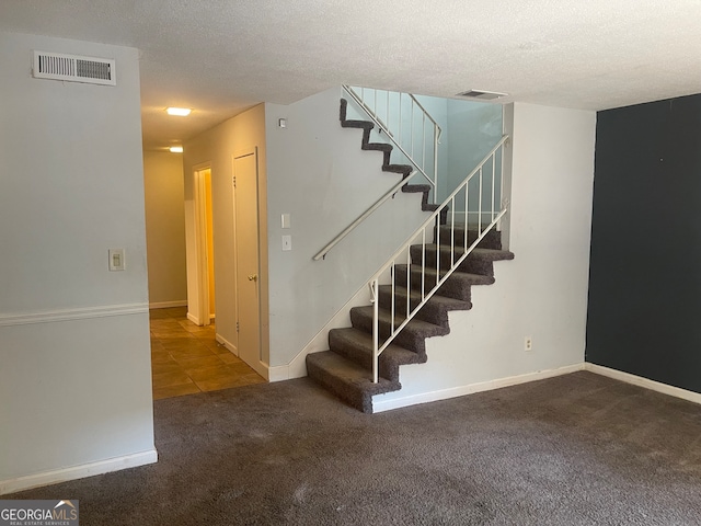 staircase featuring carpet and a textured ceiling