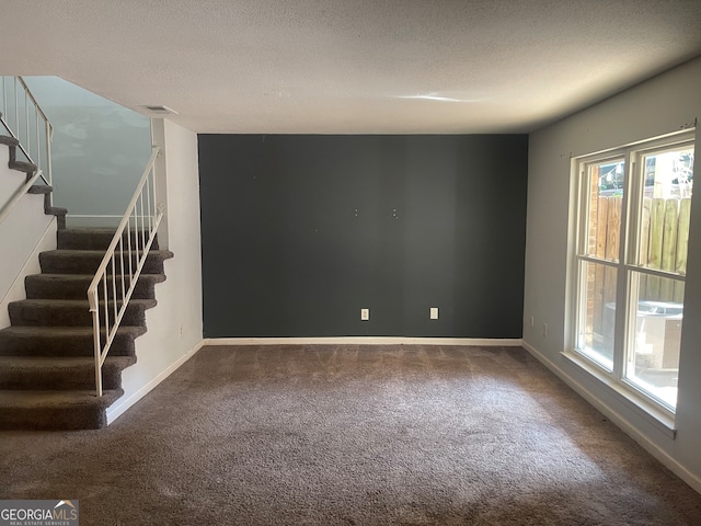 empty room with carpet floors and a textured ceiling