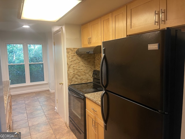 kitchen featuring light stone counters, light tile patterned floors, black appliances, light brown cabinetry, and decorative backsplash