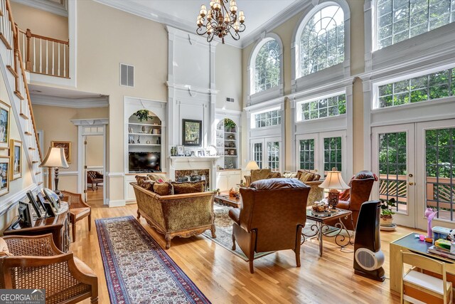 living room featuring a fireplace, french doors, light hardwood / wood-style floors, and a towering ceiling