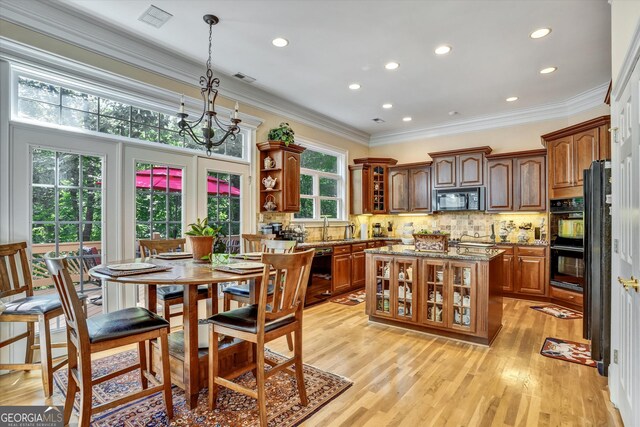 kitchen with dark stone countertops, light hardwood / wood-style flooring, black appliances, and a wealth of natural light