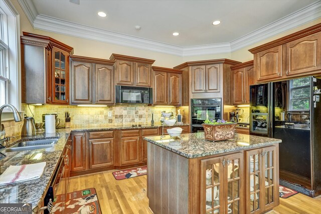 kitchen featuring sink, light stone counters, light wood-type flooring, and black appliances