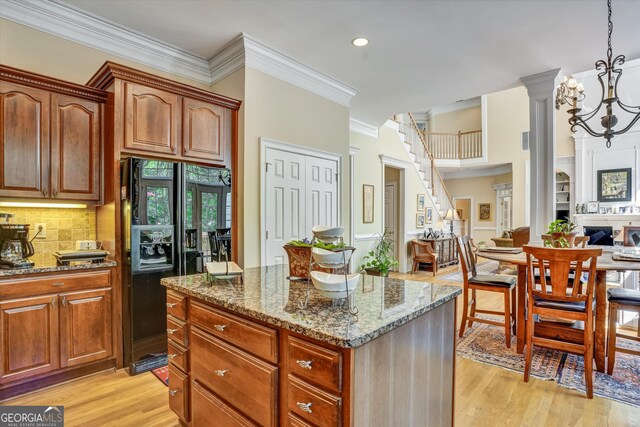 kitchen featuring dark stone countertops, a center island, hanging light fixtures, and light hardwood / wood-style floors