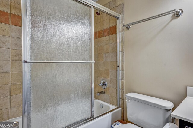 bathroom featuring bath / shower combo with glass door and toilet