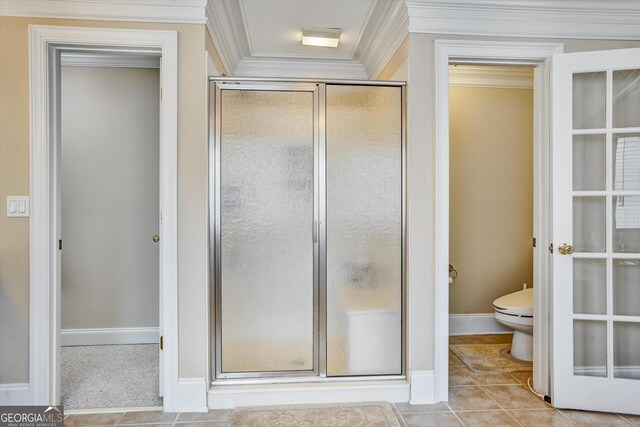 bathroom with tile patterned flooring, a shower with door, crown molding, and toilet