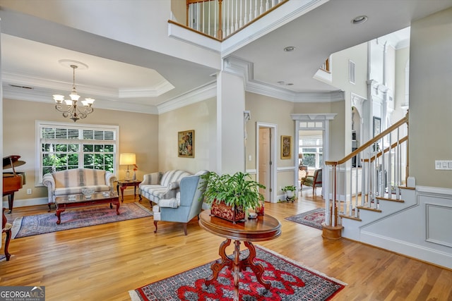 foyer entrance featuring an inviting chandelier, light wood-type flooring, a tray ceiling, and ornamental molding