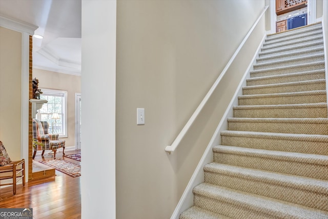 staircase featuring ornamental molding and hardwood / wood-style flooring