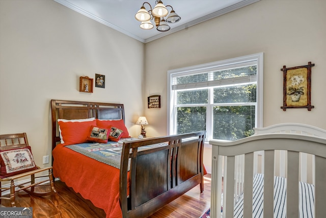 bedroom with ornamental molding, an inviting chandelier, and hardwood / wood-style flooring