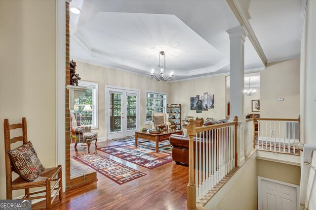 living room featuring wood-type flooring, a raised ceiling, and an inviting chandelier