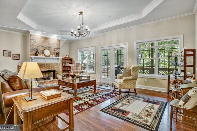 living room with an inviting chandelier, wood-type flooring, a fireplace, and crown molding