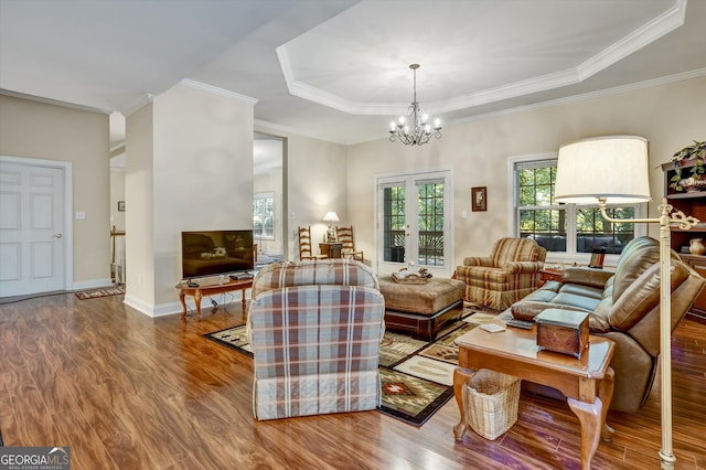 living room featuring an inviting chandelier, hardwood / wood-style flooring, french doors, and a tray ceiling