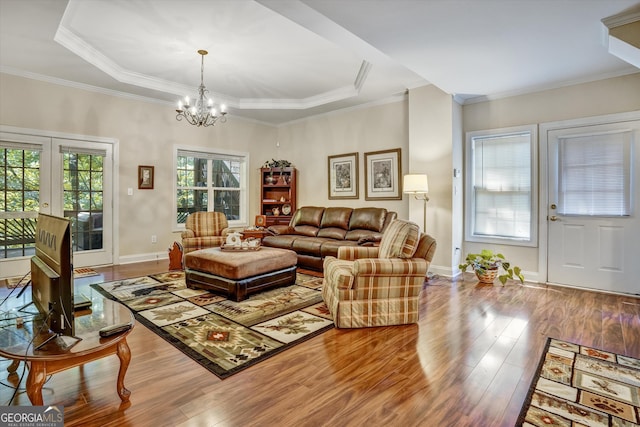 living room featuring crown molding, a tray ceiling, a chandelier, and hardwood / wood-style flooring