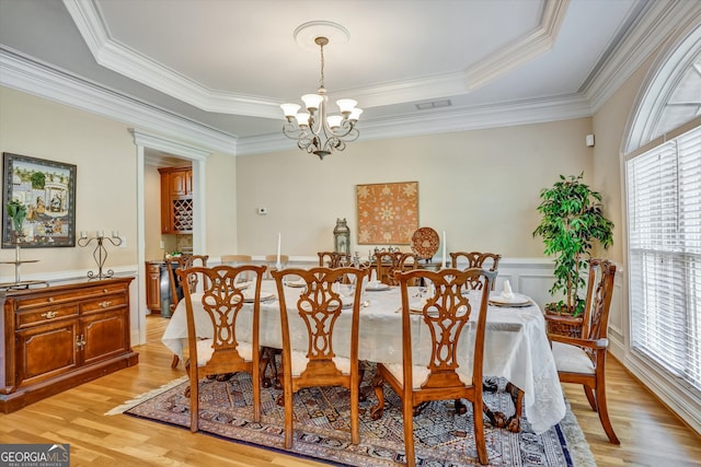 dining room with light hardwood / wood-style floors, a raised ceiling, plenty of natural light, and a chandelier