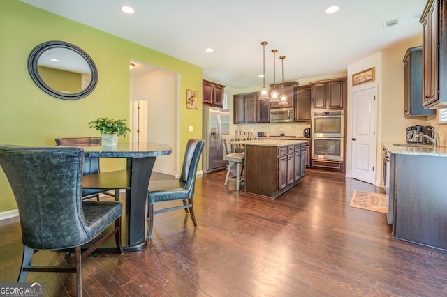 kitchen with a kitchen island, tasteful backsplash, stainless steel appliances, and dark wood-type flooring