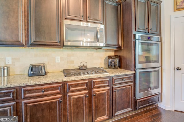 445 Brickstone Way, Covington, GA 30016 - kitchen with stainless steel appliances, decorative backsplash, light stone counters, and dark wood-style floors