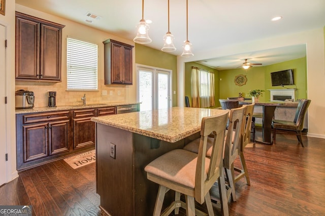 445 Brickstone Way, Covington, GA 30016 - kitchen with dark wood-type flooring, a kitchen island, ceiling fan, light stone countertops, and hanging light fixtures