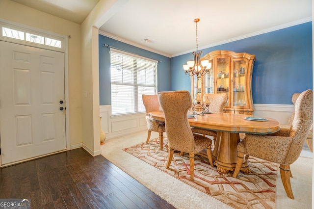 dining room with ornamental molding, an inviting chandelier, and hardwood / wood-style flooring