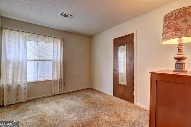 carpeted spare room with a textured ceiling