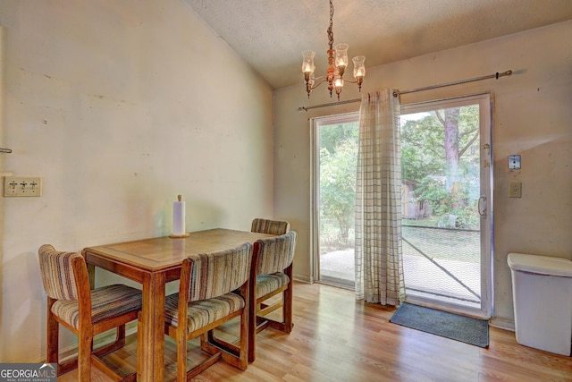 dining room with lofted ceiling, an inviting chandelier, a textured ceiling, and light hardwood / wood-style floors