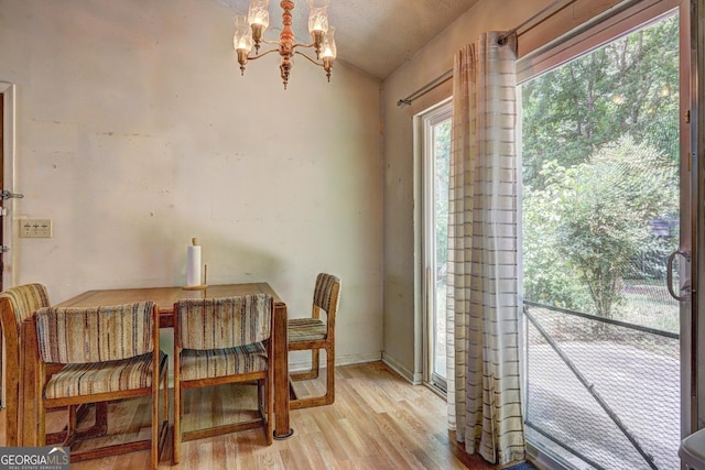 dining space with an inviting chandelier, vaulted ceiling, and light hardwood / wood-style floors