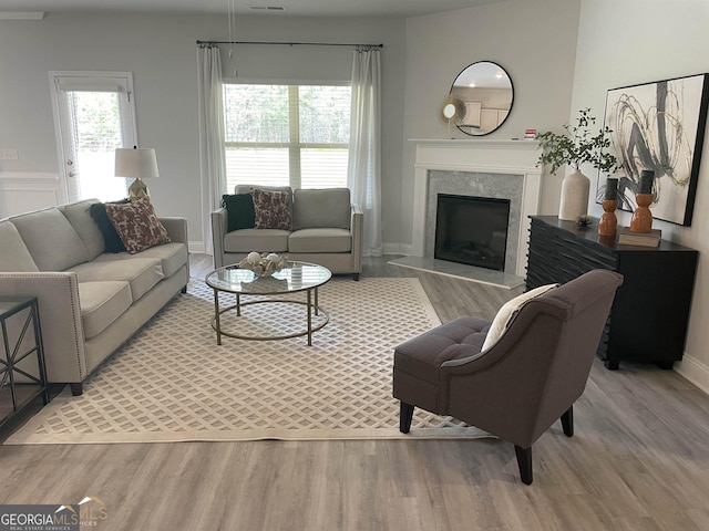 living room with a premium fireplace, plenty of natural light, and light hardwood / wood-style flooring