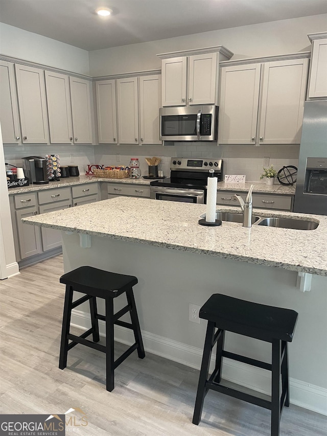 kitchen featuring light stone countertops, appliances with stainless steel finishes, and a kitchen bar