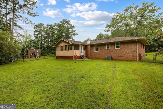 back of property featuring a yard, central AC unit, and a storage shed