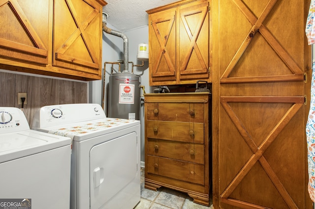 washroom featuring gas water heater, washer and clothes dryer, cabinets, and a textured ceiling