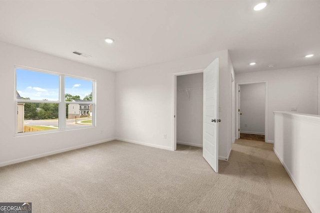 unfurnished bedroom with light colored carpet and a closet