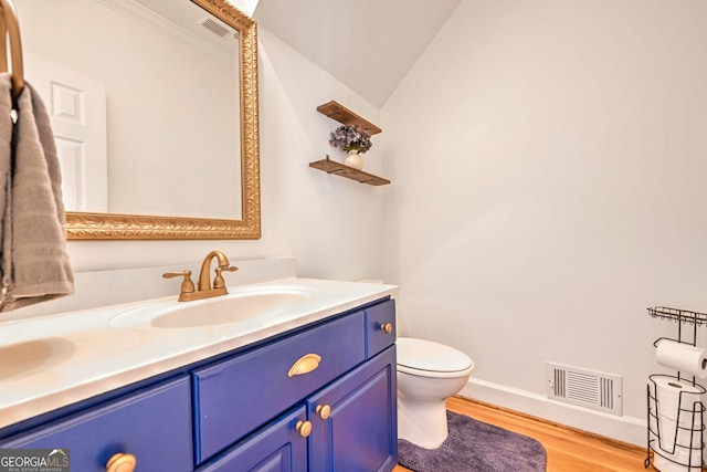 bathroom with wood-type flooring, vaulted ceiling, vanity, and toilet