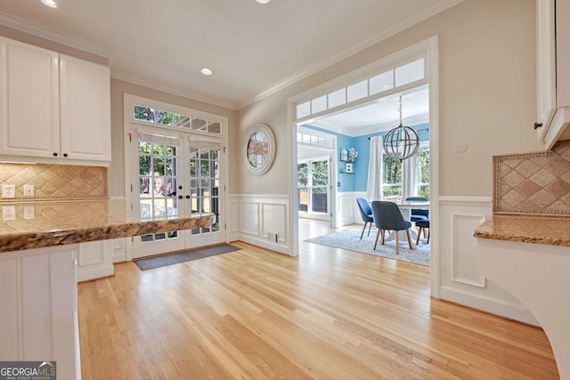 kitchen featuring pendant lighting, light hardwood / wood-style flooring, backsplash, and white cabinets