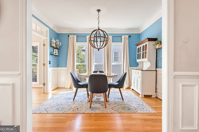 dining space featuring light hardwood / wood-style floors, crown molding, and an inviting chandelier