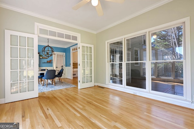 unfurnished sunroom featuring ceiling fan with notable chandelier and french doors